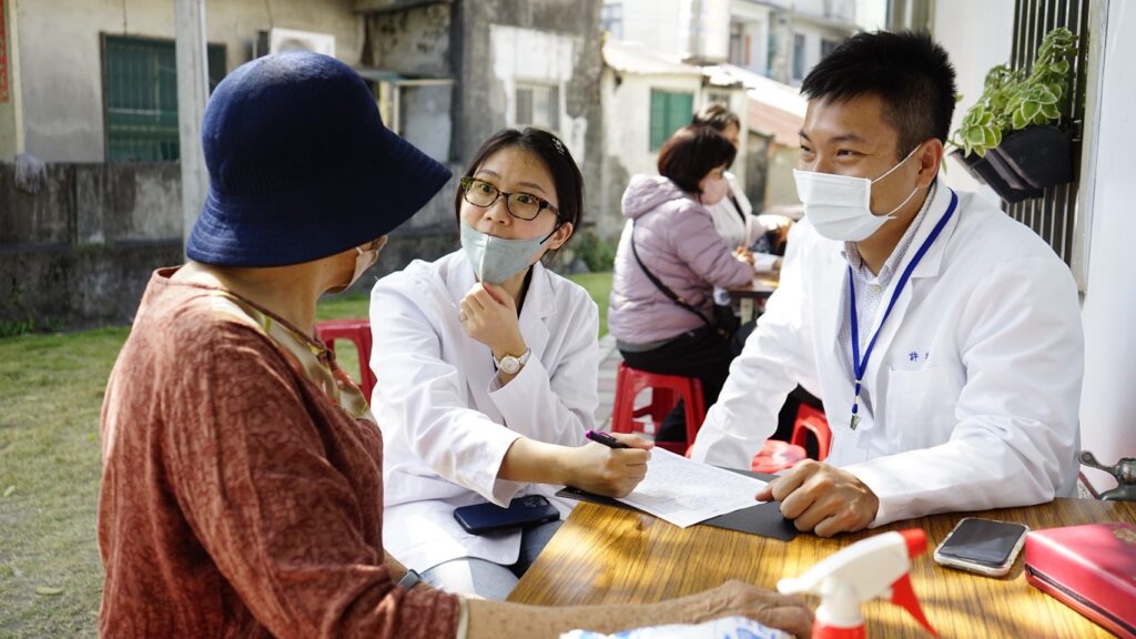 醫療服務隊初診組員耐心詢問里民狀況，透過細心紀錄與觀察，確保長者獲得精準的初步醫療評估，展現後中醫系學子視病如親的服務熱忱。（資料畫面來源：義守大學提供）