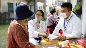 醫療服務隊初診組員耐心詢問里民狀況，透過細心紀錄與觀察，確保長者獲得精準的初步醫療評估，展現後中醫系學子視病如親的服務熱忱。（資料畫面來源：義守大學提供）